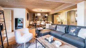 A modern living room with a grey sofa, white furry chair, and a coffee table with a tray. - PADOUK- Apartment w/ hot tub in Courchevel Moriond (Courchevel)