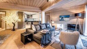 A modern living room with a sofa, coffee table, and a fluffy chair. There is a wooden ceiling and a painting on the wall. - PADOUK- Apartment w/ hot tub in Courchevel Moriond (Courchevel)