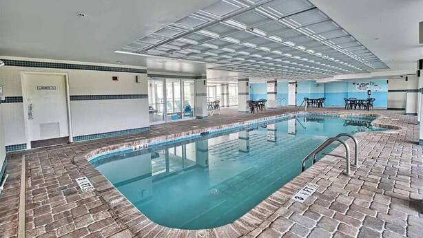 A swimming pool with a tiled deck, a ceiling with skylights, and a door labeled "LADIES".