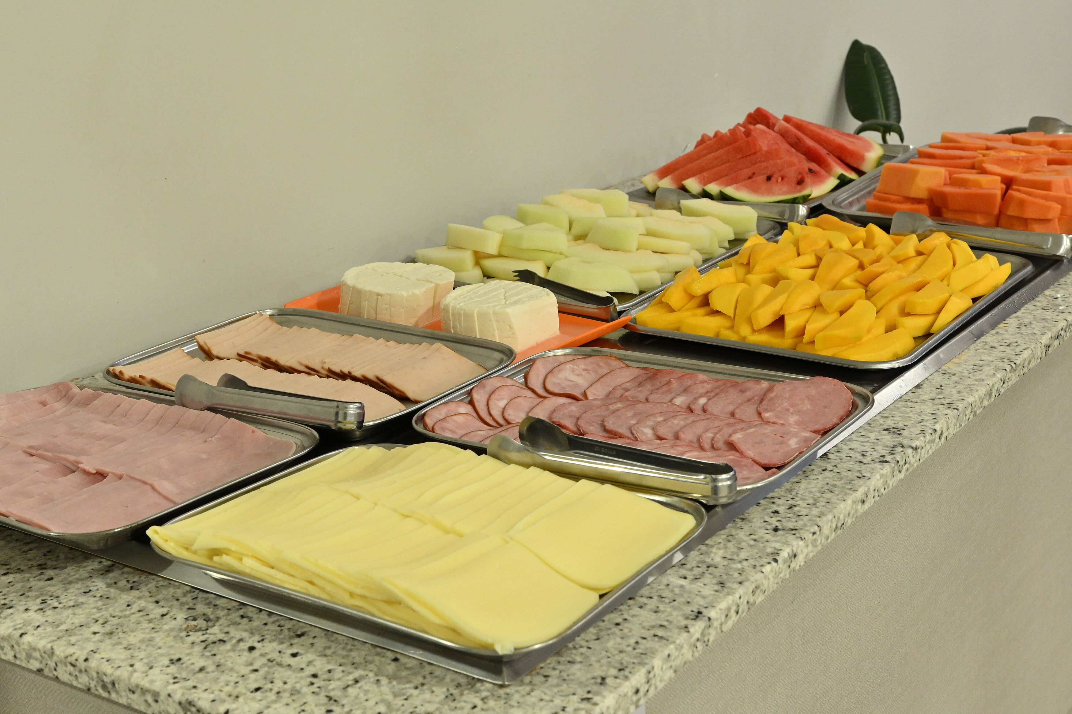 Un buffet proposant une variété de plats, notamment des viandes, des fromages, des fruits et des légumes.