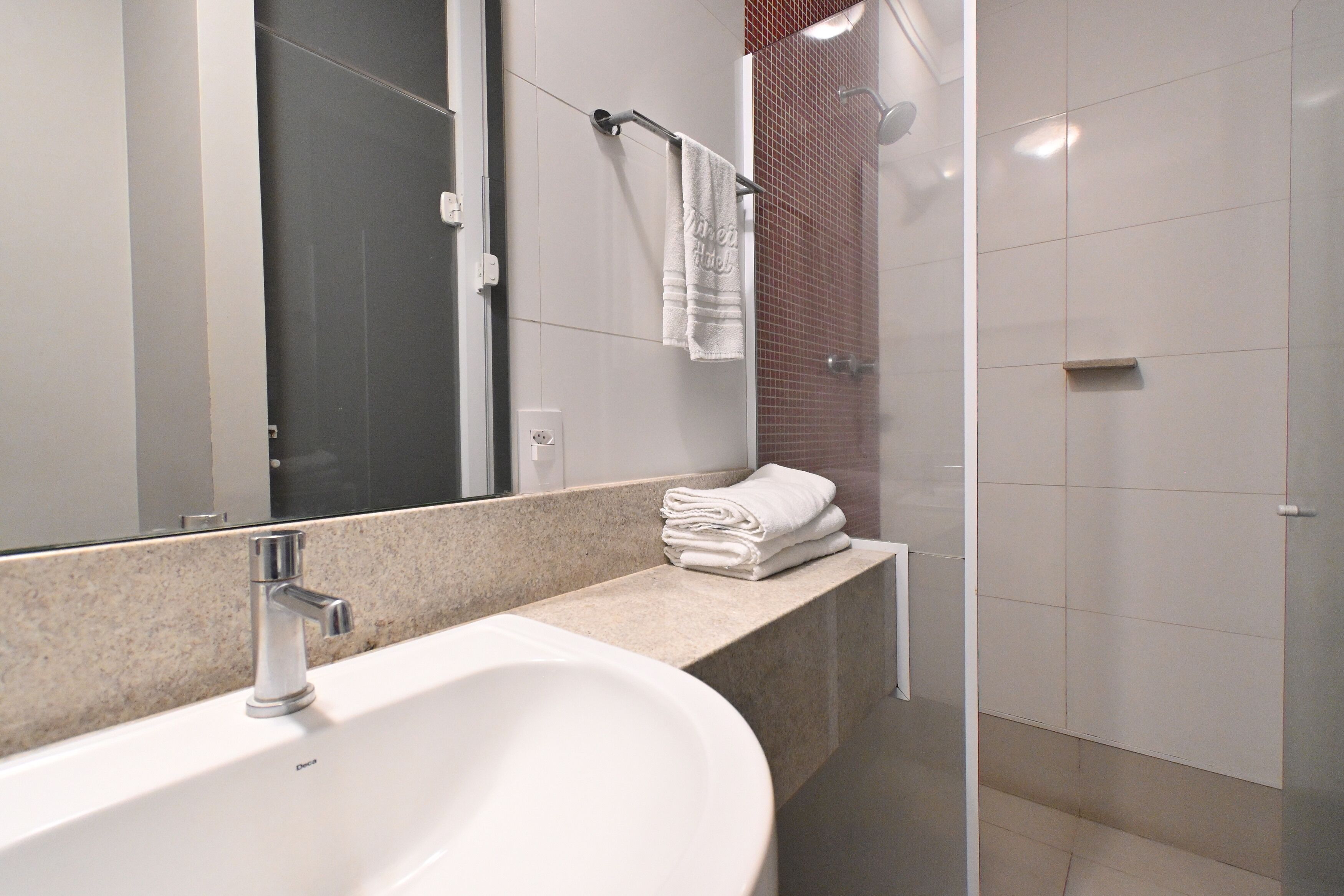 A modern bathroom with a large sink, a mirror, and a glass shower enclosure.