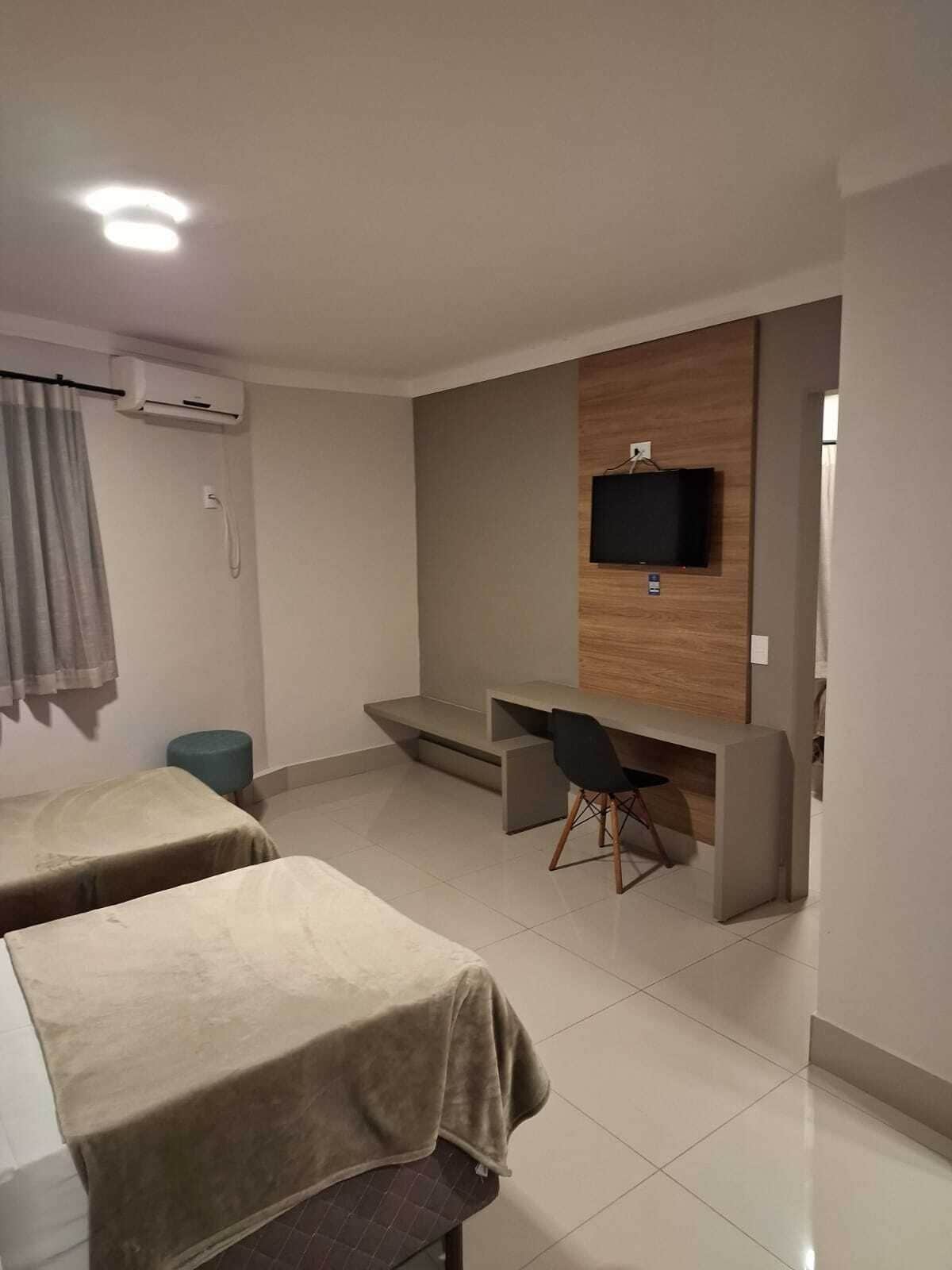 Una habitación de hotel con dos camas, un escritorio, una silla, un televisor y un equipo de aire acondicionado.