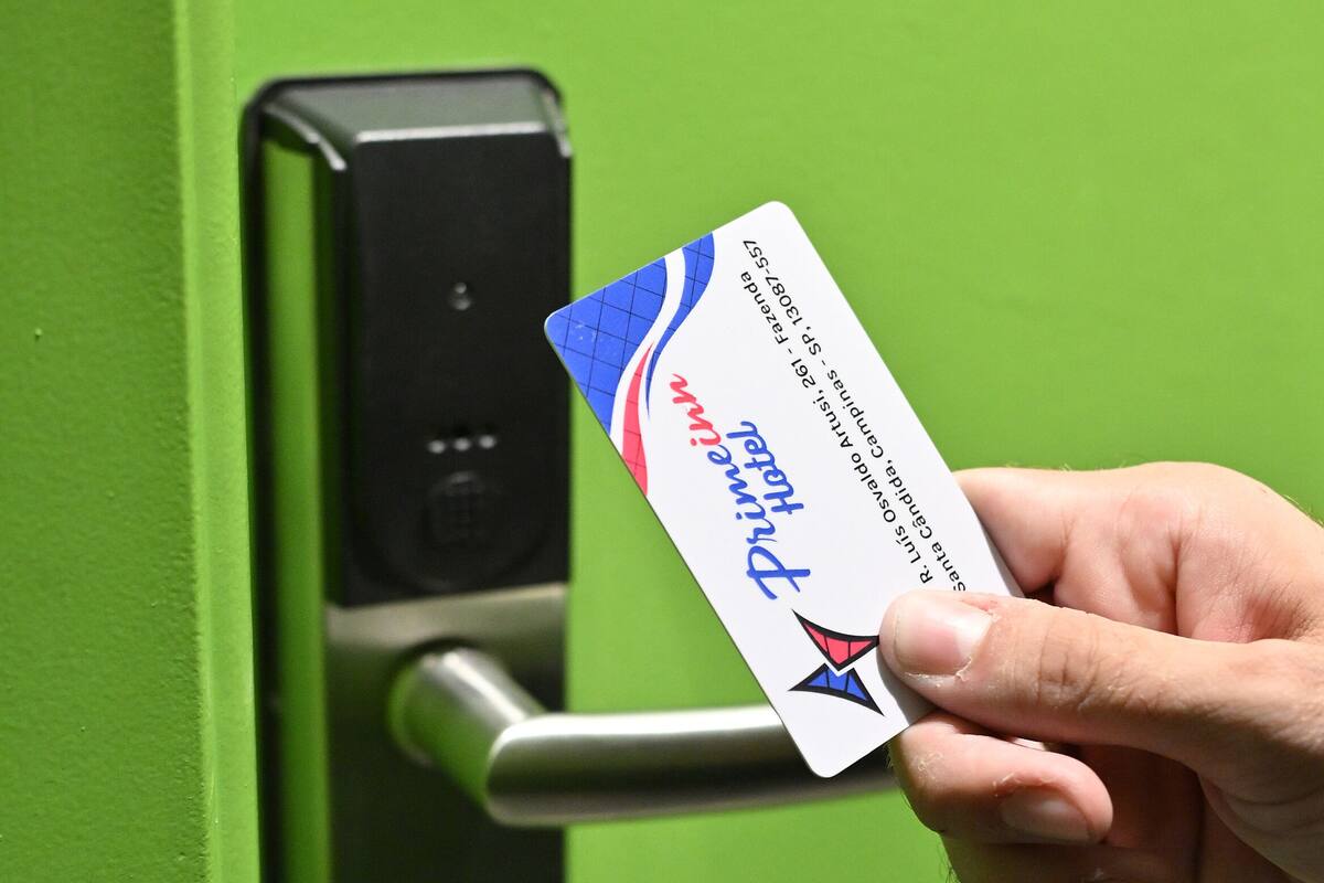 A hand holding a card near a door lock.