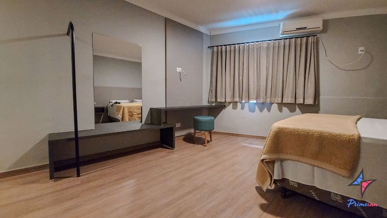 Un dormitorio moderno con cama, un banco, un espejo y una ventana con cortinas.