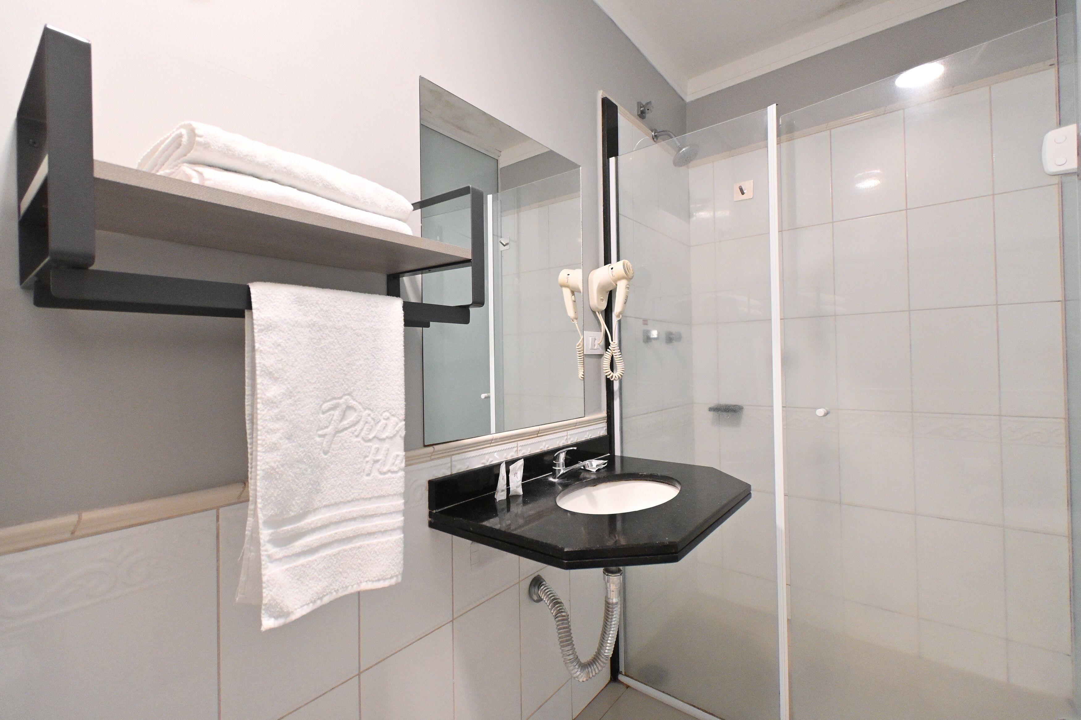 Een moderne badkamer met een zwart wastafel, een handdoekhouder met een opgevouwen handdoek, een spiegel en een douche met glazen wanden.