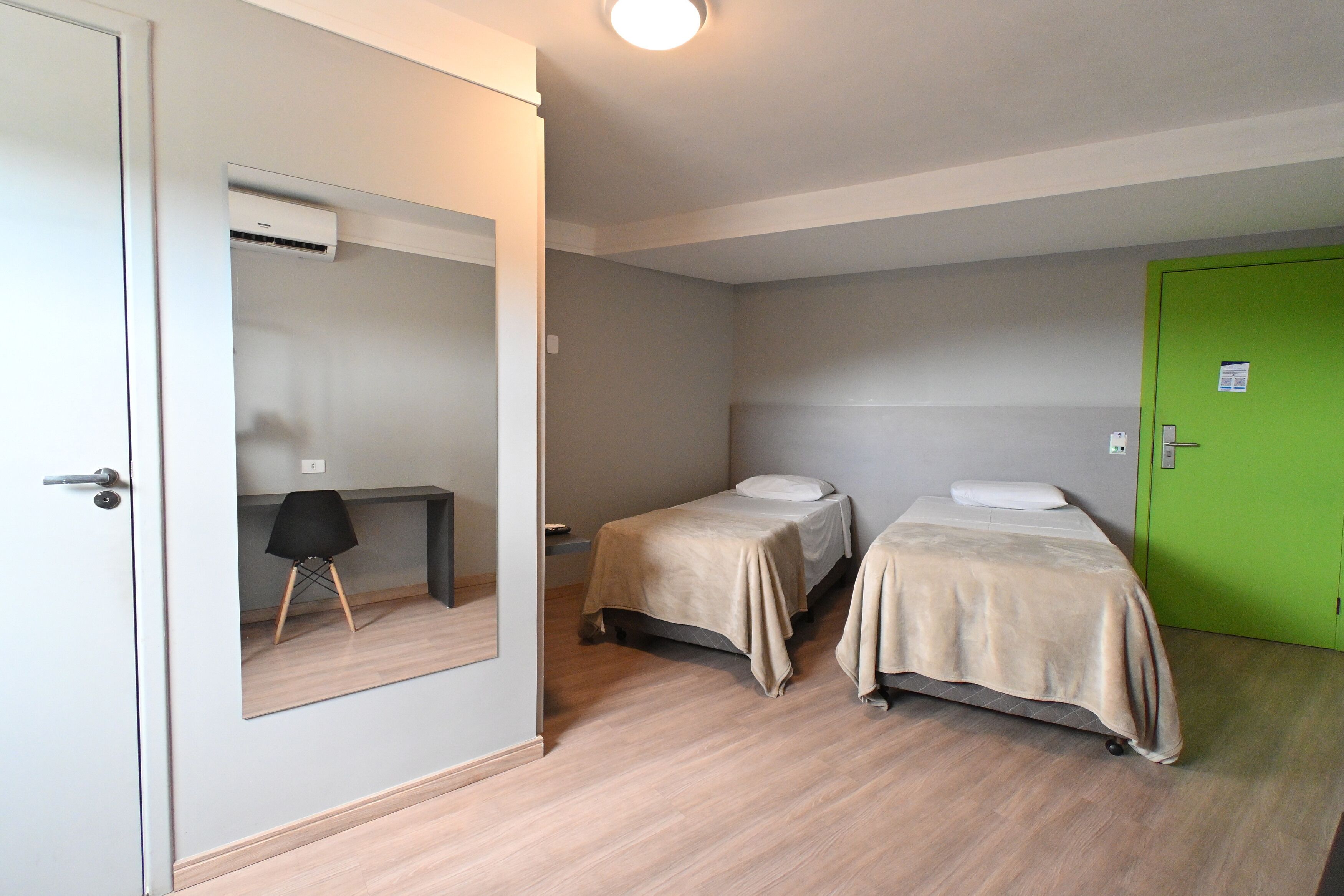 Una habitación con dos camas, un escritorio y un espejo.