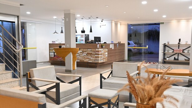 Un moderno vestíbulo de hotel con una recepción, zona de estar y una escalera.
