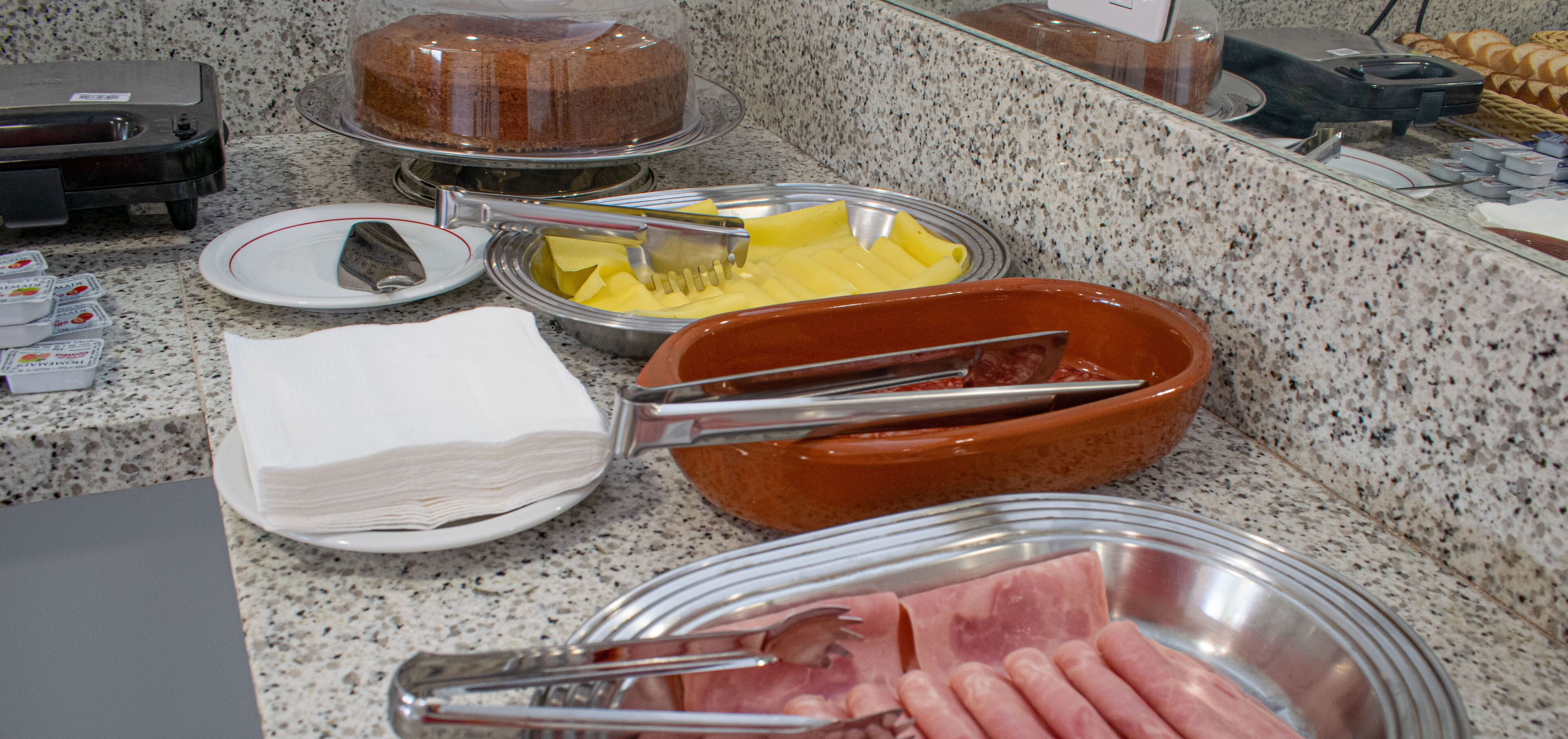 A buffet with various food items including a cake, cheese, and meat.