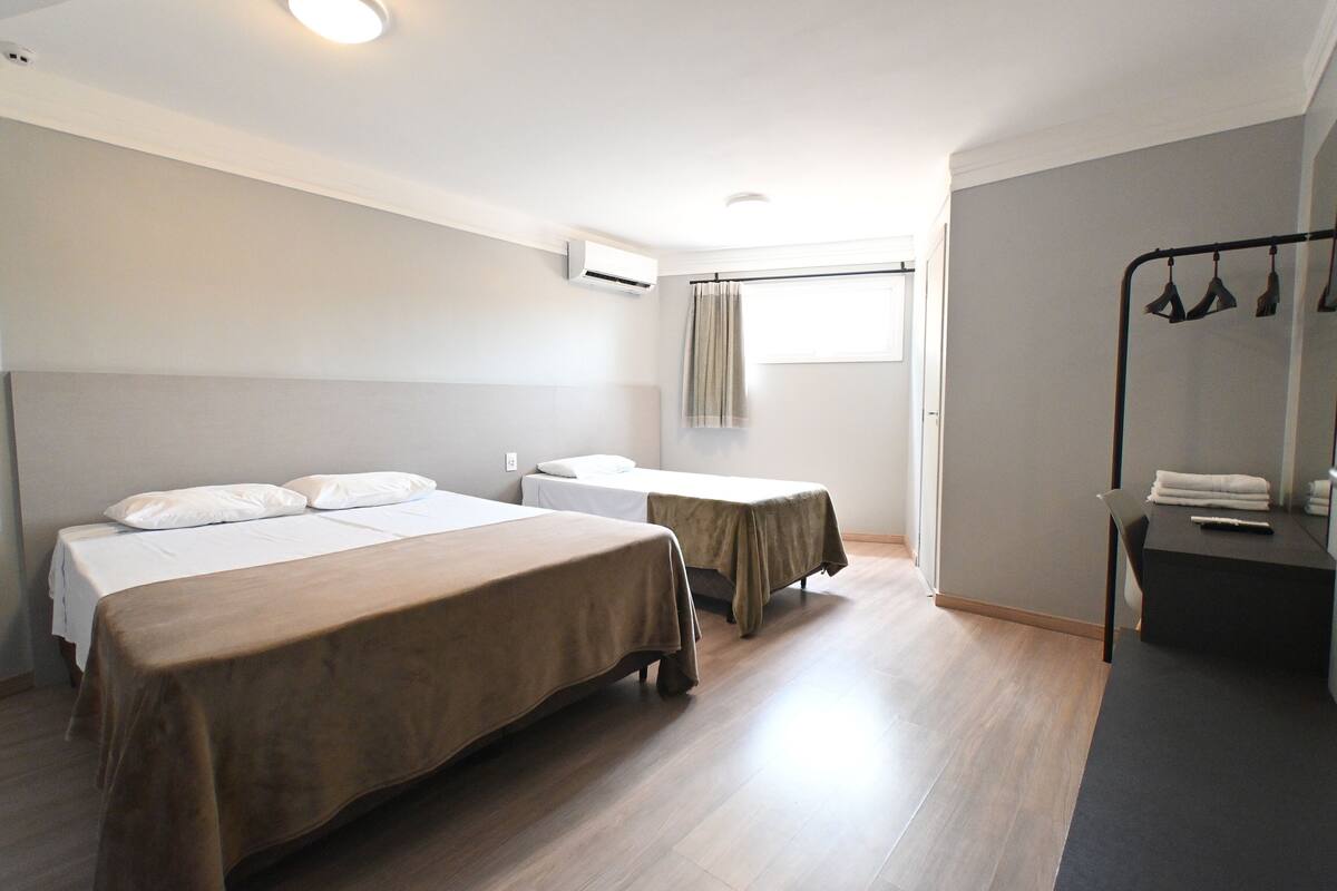 A hotel room with two beds, a desk, and a chair.