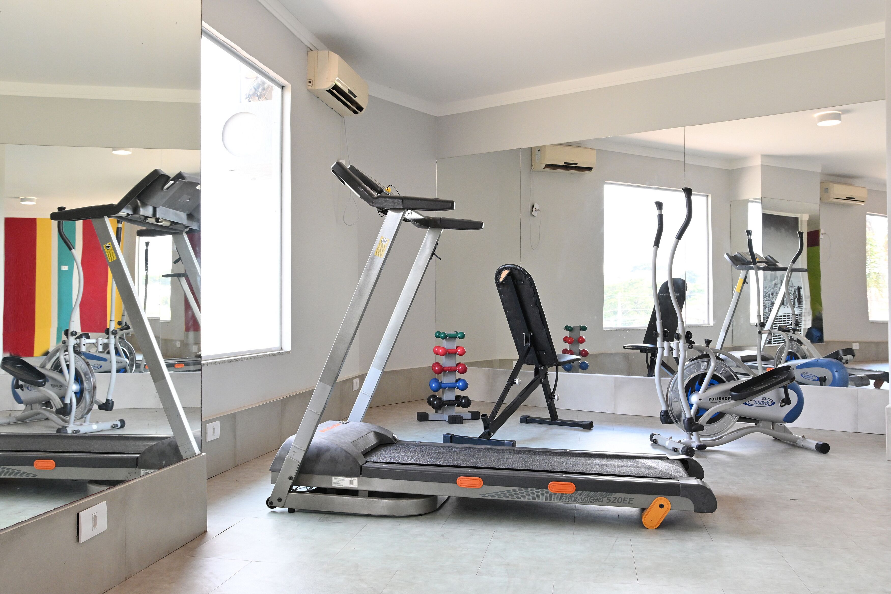 A gym with treadmills, ellipticals, and a weight rack.