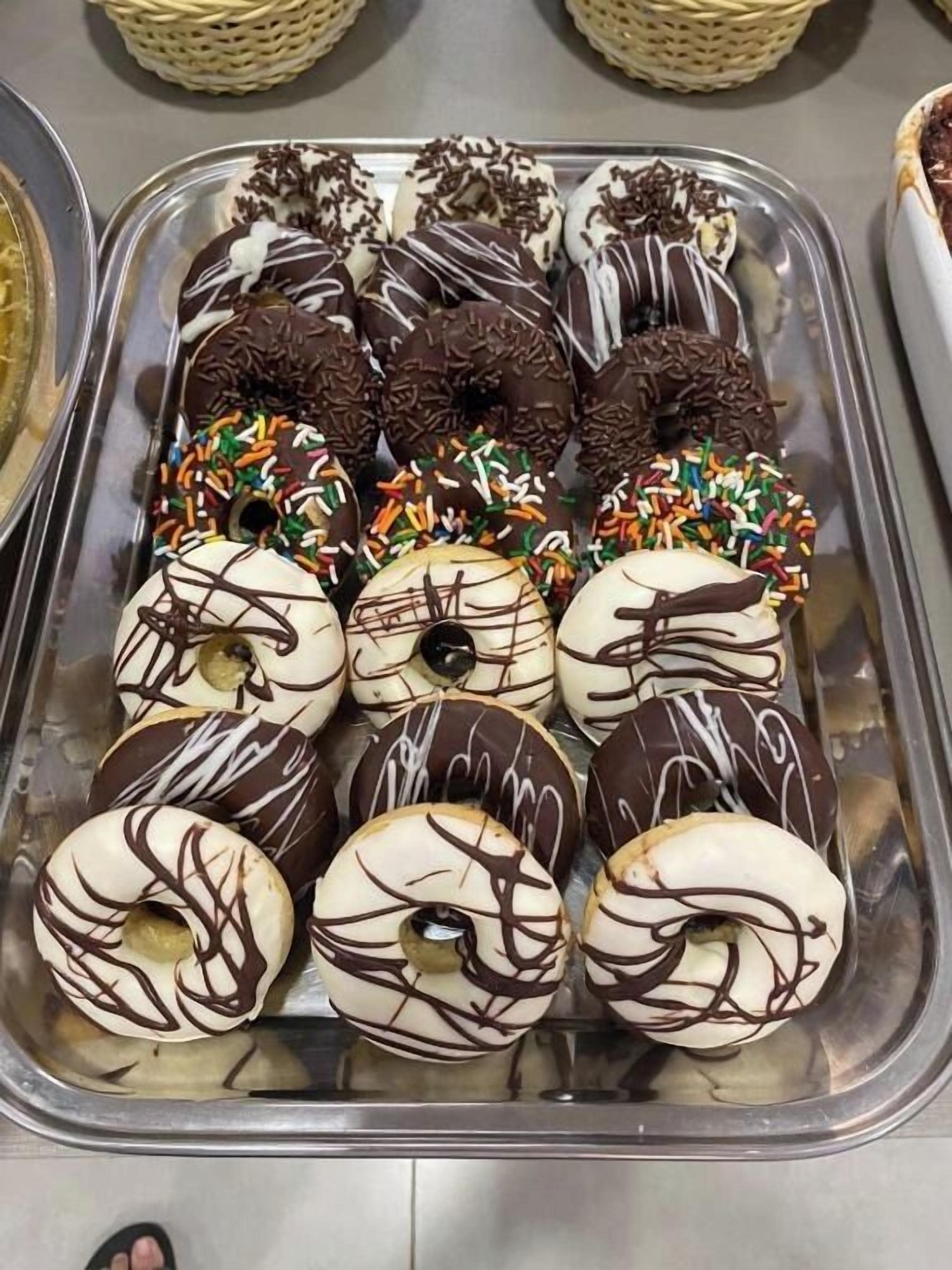 A tray of assorted donuts with chocolate and white icing, some with sprinkles.