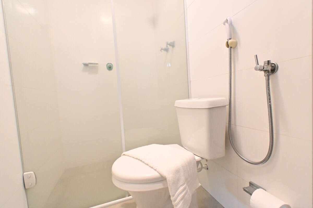 A modern bathroom with a glass-enclosed shower, a white toilet, and a handheld showerhead.