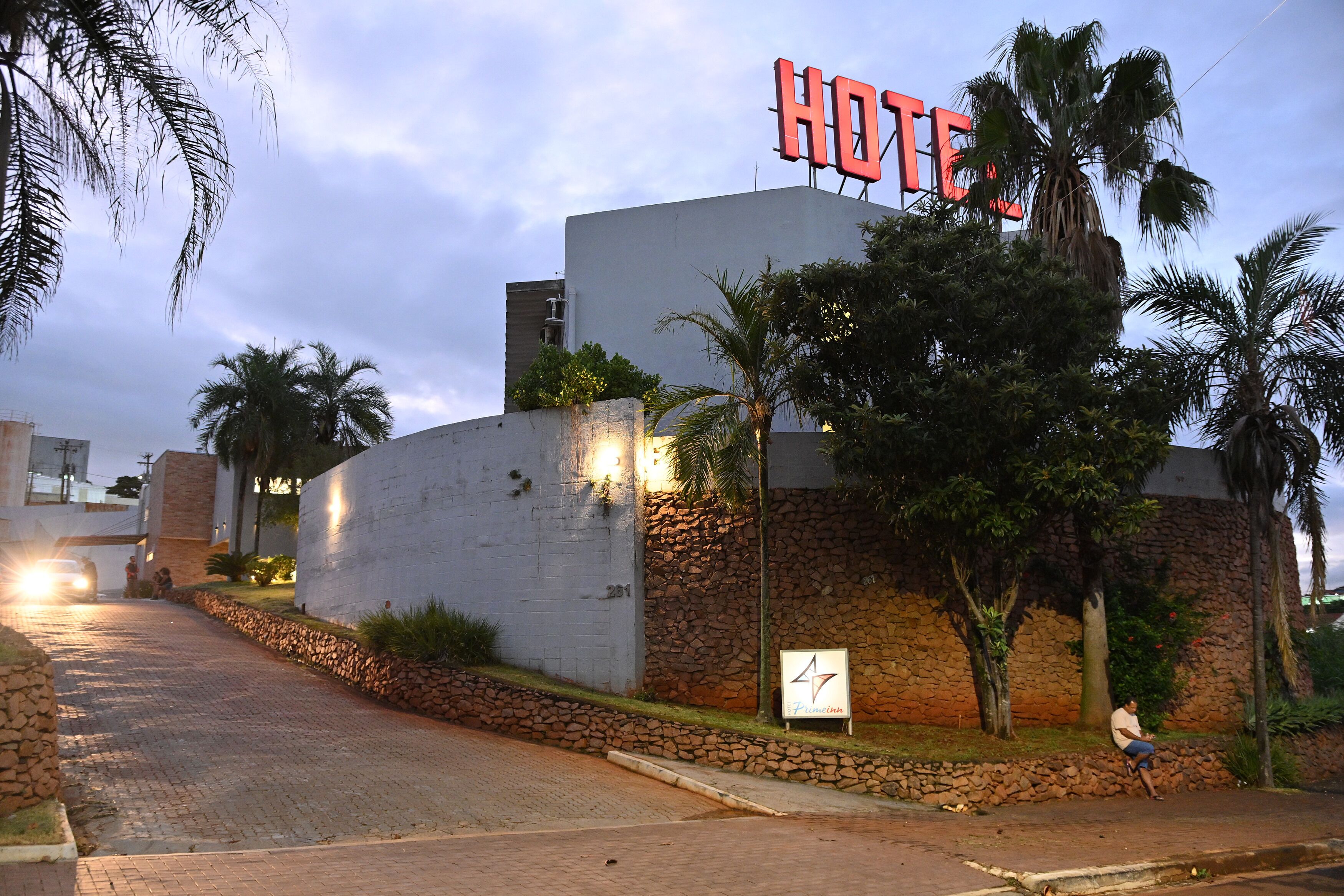 A hotel with a prominent "HOTEL" sign, a stone wall, and a paved driveway.