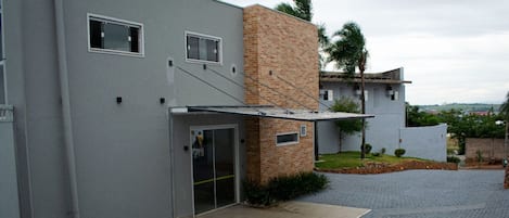 Un edificio moderno con fachada gris, sección de ladrillo y vestíbulo cubierto.