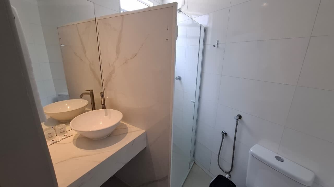 Casa de banho moderna com duas pias, chuveiro e sanita.