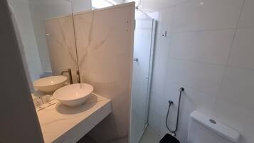 Casa de banho moderna com duas pias, chuveiro e sanita.