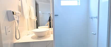 Un baño con lavamanos blanco, secador de pelo y espejo.