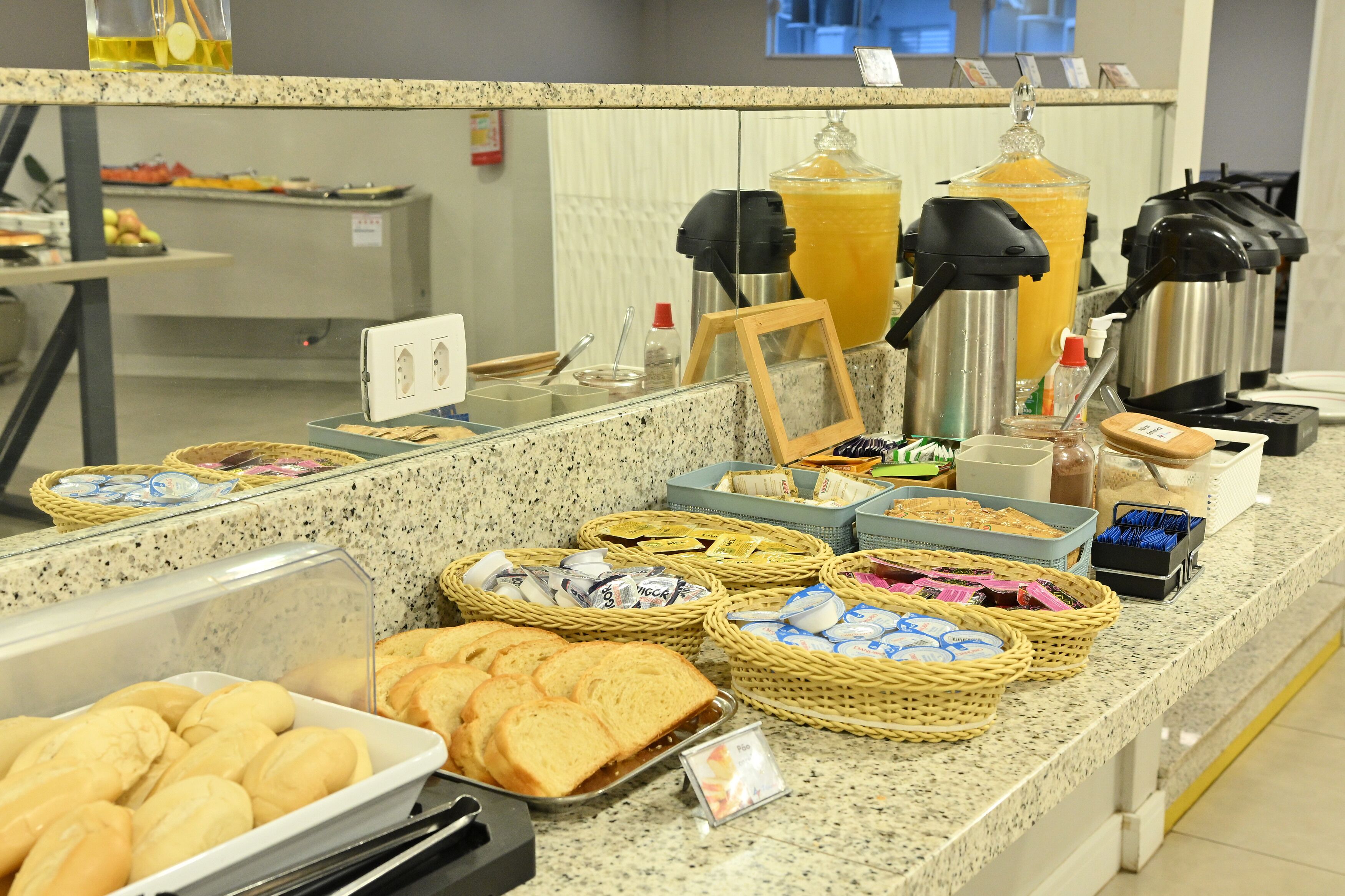 A buffet counter with various food items, including bread, pastries, and condiments.