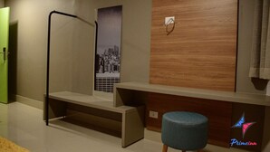 Una habitación de hotel moderna con una pared de acento de madera, un cartel con un paisaje urbano, un banco y un otoman azul.
