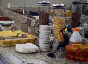 A buffet setup with various food items, including cereal, nuts, and a cake.