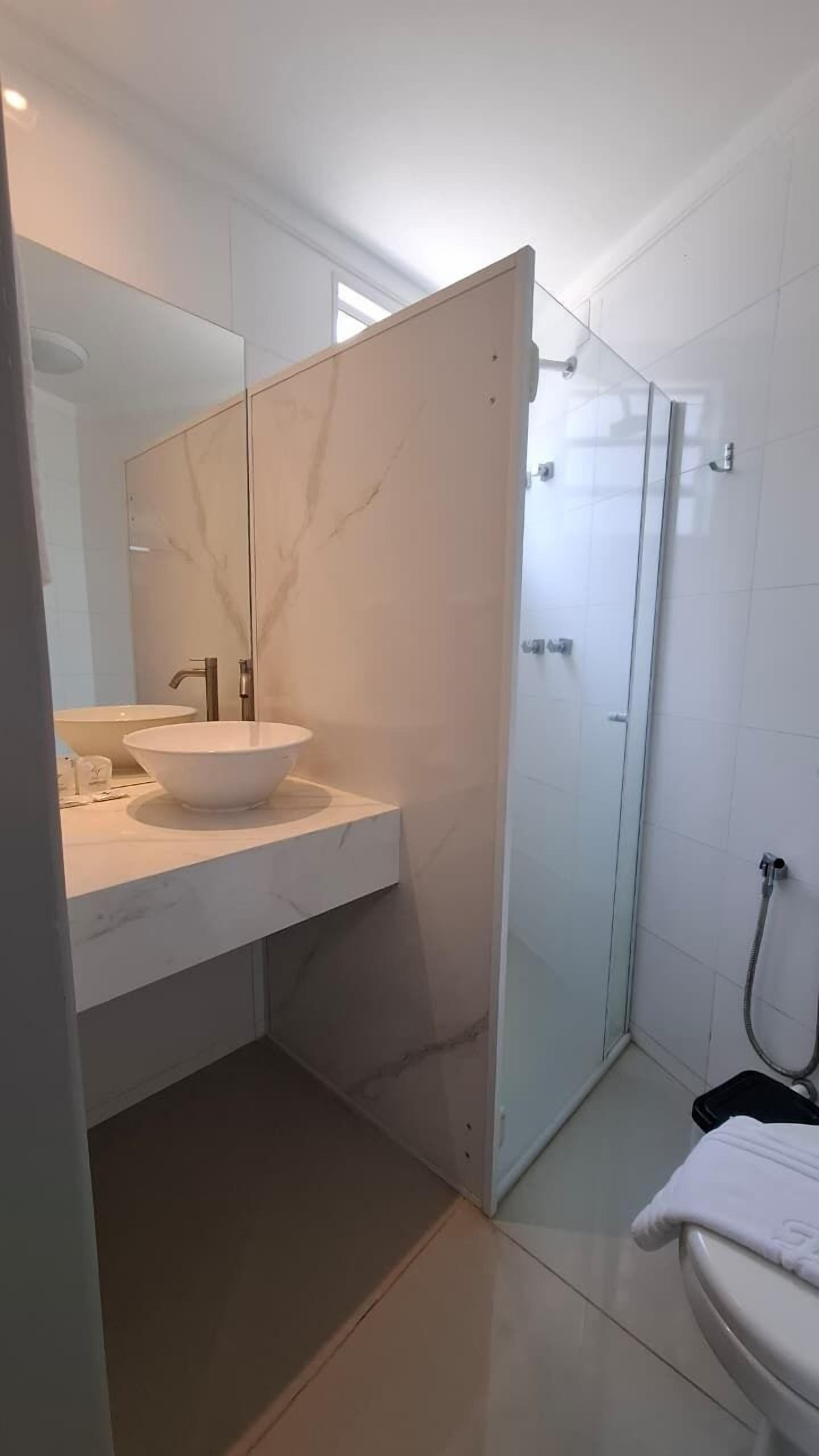 A modern bathroom with a large mirror, a white sink, and a glass shower enclosure.