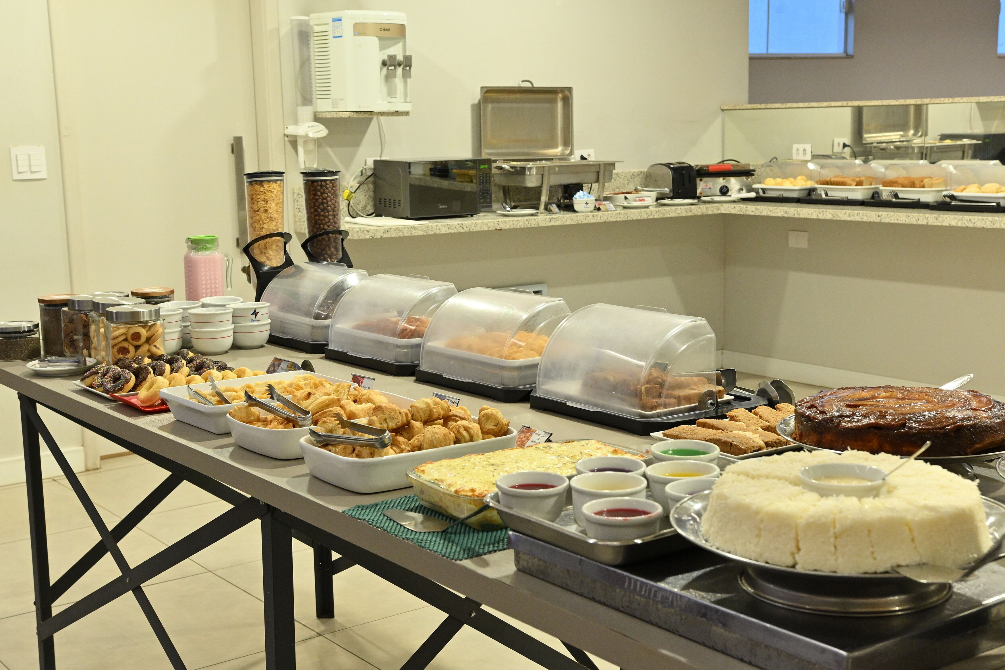 Un bufé con diversos alimentos y recipientes, incluyendo un pastel y varios cuencos de salsas.