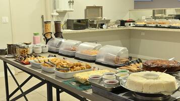 Un bufé con diversos alimentos y recipientes, incluyendo un pastel y varios cuencos de salsas.