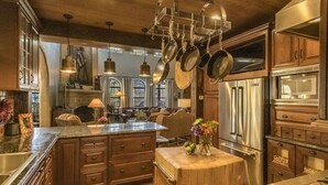 A spacious kitchen with a large island, stainless steel appliances, and wooden cabinetry. - Unique mountain home with hot tub (Angel Fire)