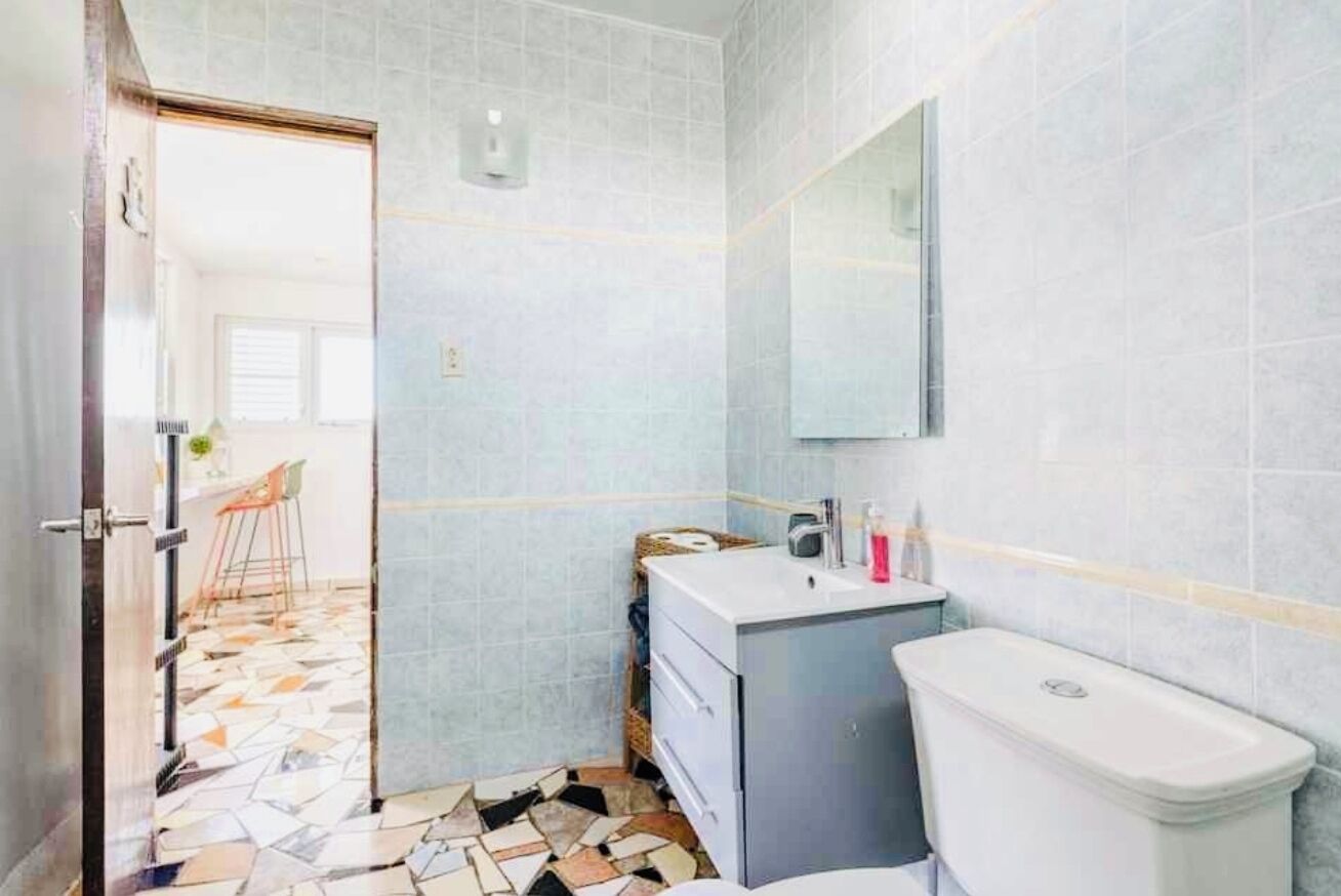 Une salle de bain avec un sol carrelé, un lavabo, des toilettes et un miroir.