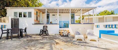 A beachside building with a covered patio, outdoor seating, and a small pool area.