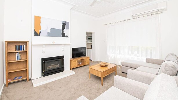 Ein Wohnzimmer mit Kamin, Fernseher, Sofa und Bücherregal.