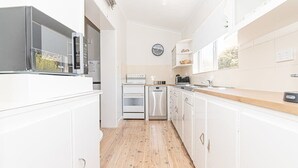 Eine moderne Küche mit weißen Schränken, einer Mikrowelle, einem Backofen und einem Geschirrspüler.