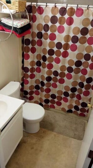 Bathroom features a white toilet, sink, and shower area with a polka dot curtain.