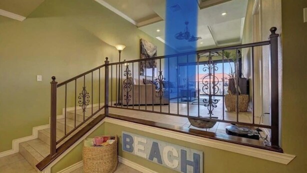 A staircase with a metal railing, a wicker basket, and a wall sign that reads "BEACH".