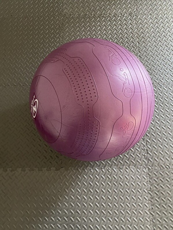 Una pelota de ejercicios rosa sobre un suelo texturizado.