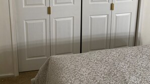 A bedroom with a bed, a white wardrobe, and a digital clock on the wall. - Elegant & Cozy 2BR Apartment with Chugach Mountain Views #1 (Anchorage)