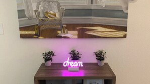 A room with a large window, a chair, a small table, and a neon sign that reads "dream". - Elegant & Cozy 2BR Apartment with Chugach Mountain Views #1 (Anchorage)