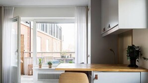 A modern kitchen with a wooden stool, a white cabinet, and a view of the outside. - Avanti Hotel (Hägersten)