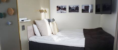 A bedroom with a bed, a TV, and three framed pictures on the wall.