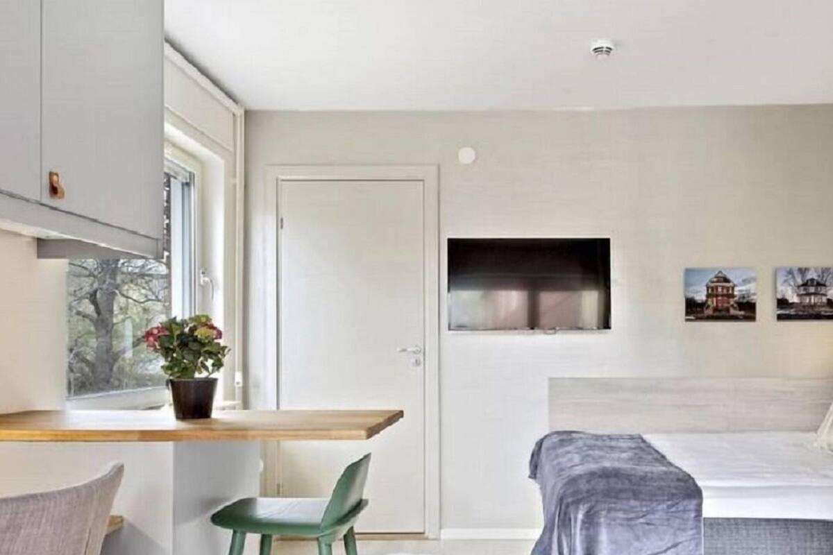 A modern bedroom with a bed, a small desk, a chair, and a window.