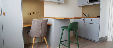 Una cocina compacta con encimera de madera, dos sillas y un microondas.
