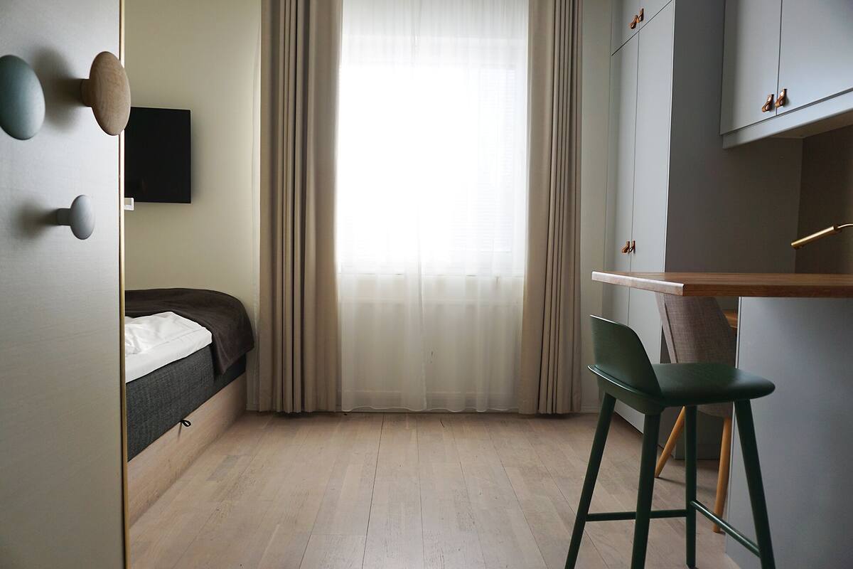 A modern hotel room with a bed, a desk, and a chair.