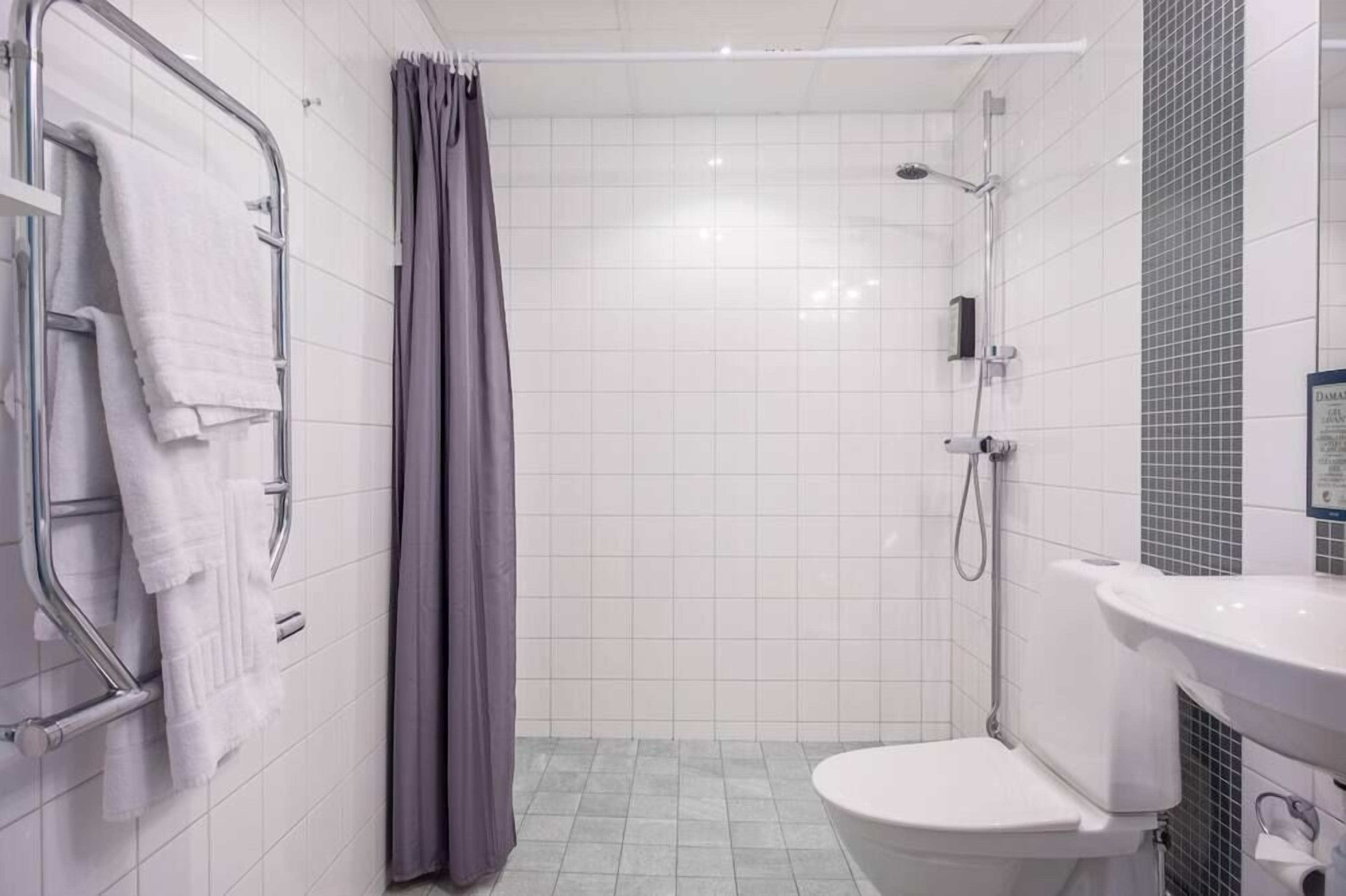 Ein modernes Badezimmer mit Dusche, Toilette und einem Handtuchhalter mit Handtüchern.
