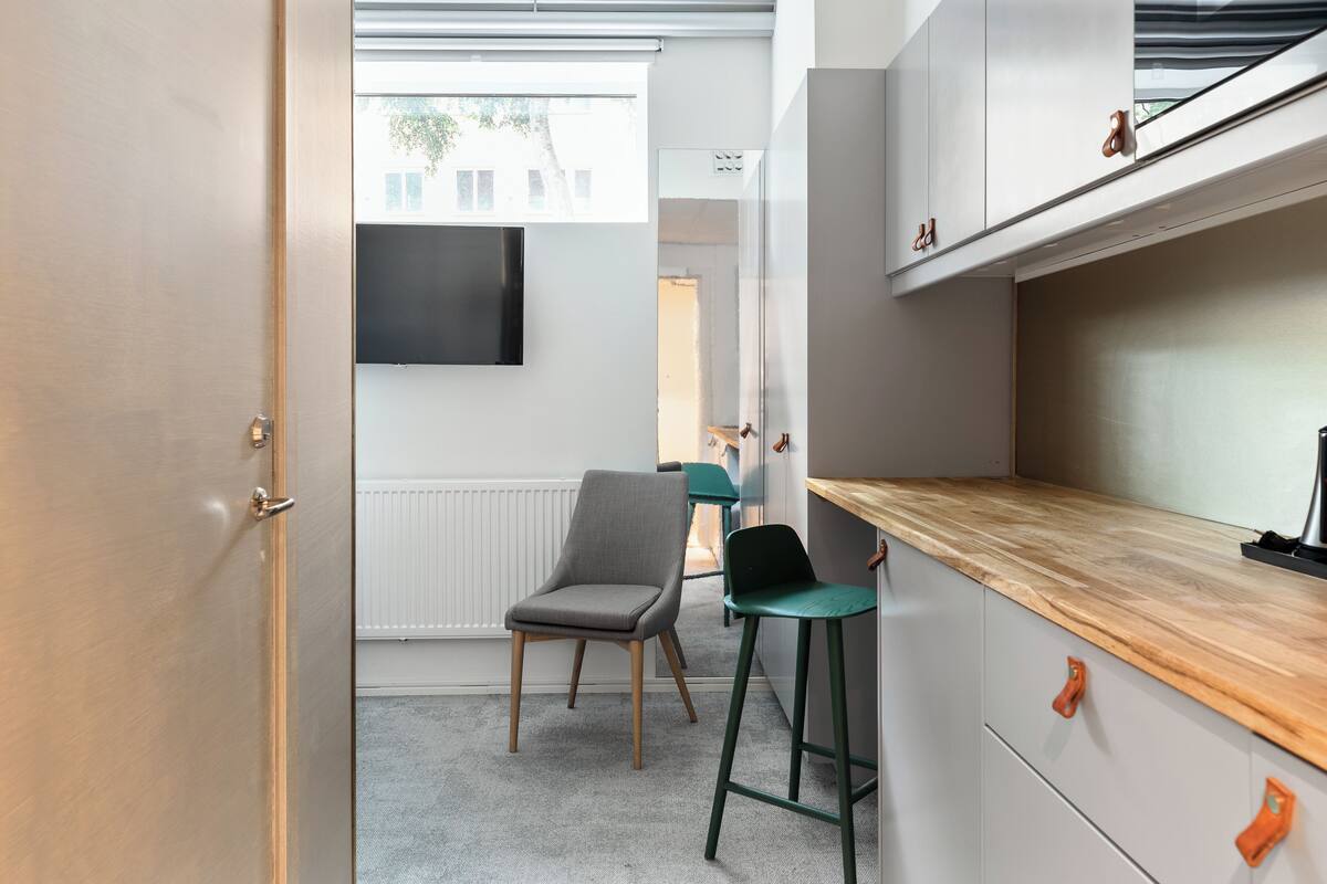 A modern kitchen with a wooden countertop, a grey chair, and a green stool.
