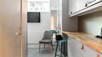 A modern kitchen with a wooden countertop, a grey chair, and a green stool.