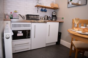 A compact kitchen with a built-in oven, a coffee maker, and a dining area with a table and chairs.