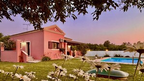 A pink house with a swimming pool, surrounded by a grassy lawn and white flowers. - Villa Cocoon Sidari with private pool (Sidari)