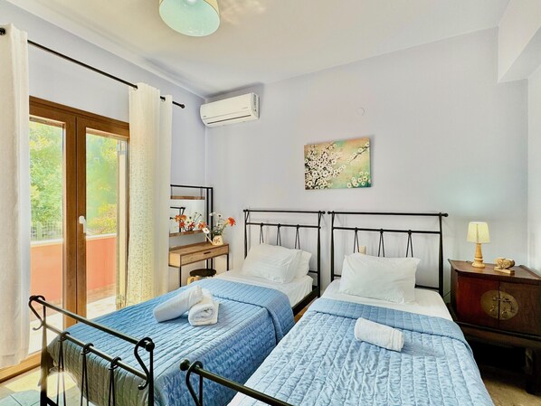 A hotel room with two beds, a wooden dresser, a mirror, and a painting on the wall. - Villa Cocoon Sidari with private pool (Sidari)