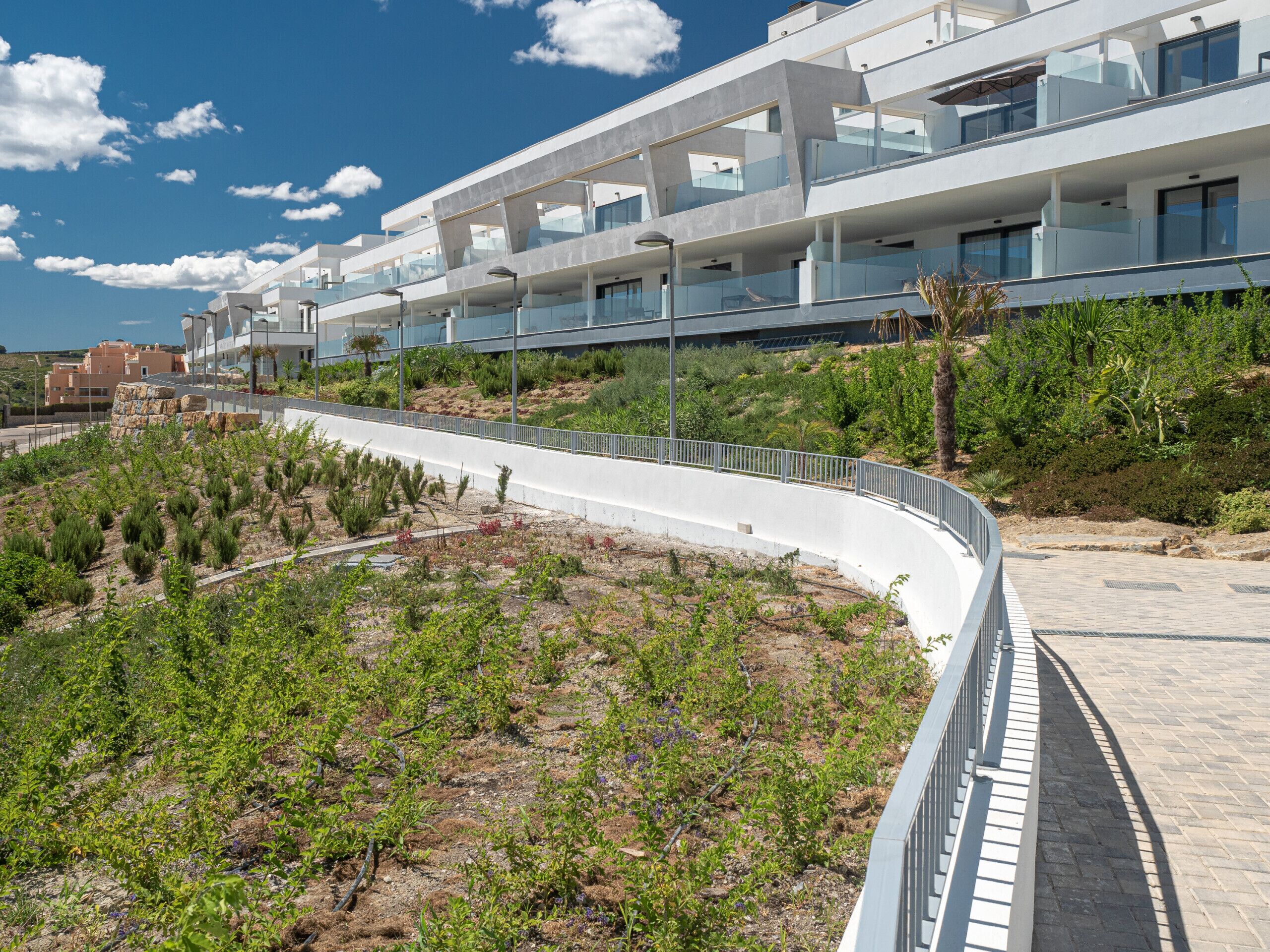 Un hôtel moderne doté d’une passerelle incurvée, d’un espace extérieur aménagé pour s’asseoir et d’un jardin paysager.