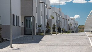 Ein modernes Gebäude mit mehreren Fenstern und Türen, einem gepflasterten Weg und Straßenlaternen.